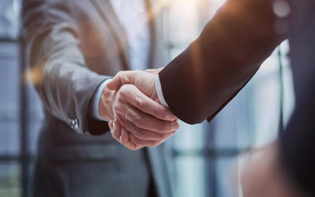 Two professional business men executive leaders shaking hands at office meeting