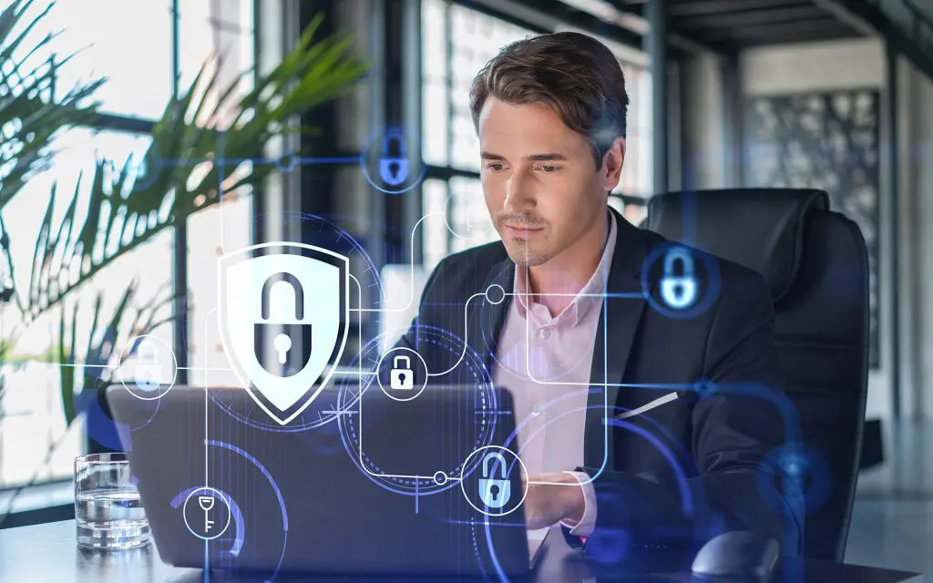 Front view of a man sitting at laptop with blue lines and lock graphical decorations, cybersecurity