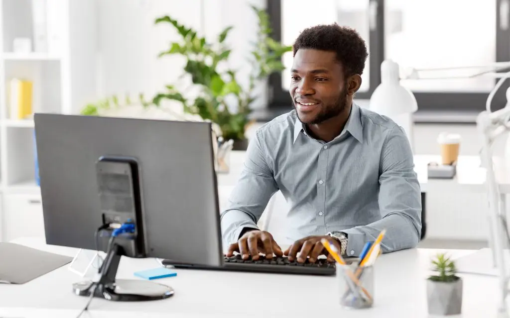 Side view of a man smiling at computer monitor