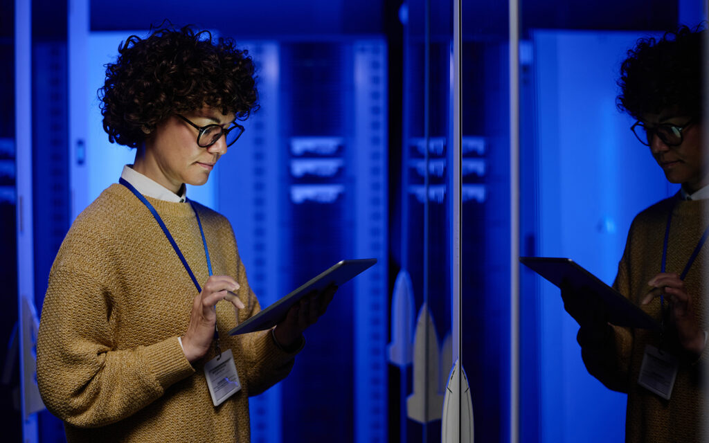 Female technician using digital tablet examining in server room